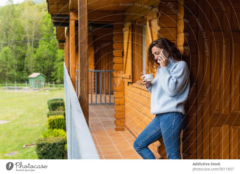 Zufriedene Frau, die auf der Terrasse eines Hauses mit ihrem Smartphone spricht reden Berge u. Gebirge Urlaub reisen Reisender benutzend Pyrenäen Feiertag