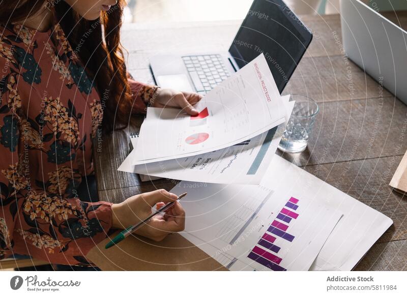 Crop ernste Frau analysiert Finanzbericht und sitzt am Schreibtisch Geschäftsfrau analysieren Analyst Arbeit Laptop Papierkram Fokus Büro Arbeitsplatz