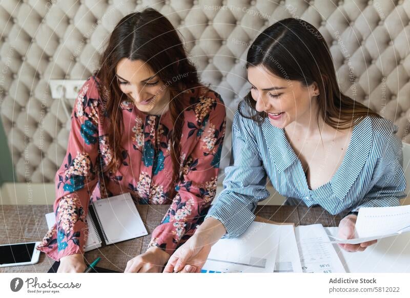 Crop-fokussierte Kolleginnen, die im Büro gemeinsam Diagramme analysieren Frauen Arbeit Papierkram Zusammensein Fokus Laptop Arbeitsplatz Kollege Arbeitsbereich