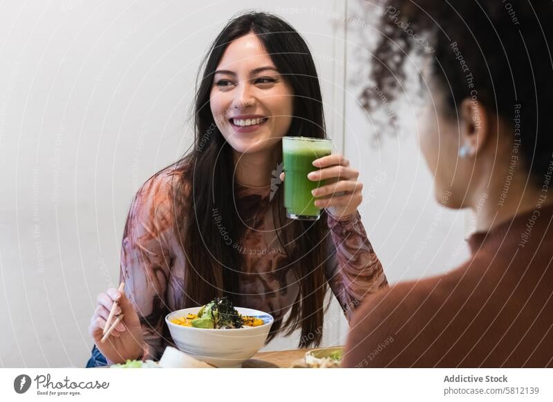 Fröhliche Frauen, die im Restaurant einen Smoothie trinken Freund Kälte Zusammensein Erfrischung Getränk heiter multiethnisch rassenübergreifend vielfältig