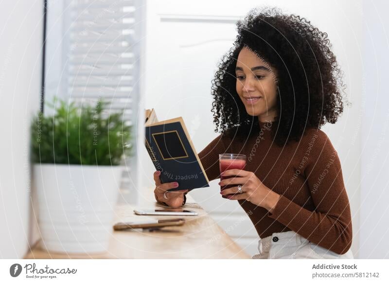 Afroamerikanische Frau trinkt Smoothie und liest ein Buch in einer Bar trinken Erfrischung lesen Getränk Sommer Kälte schwarz Afroamerikaner ethnisch Lächeln