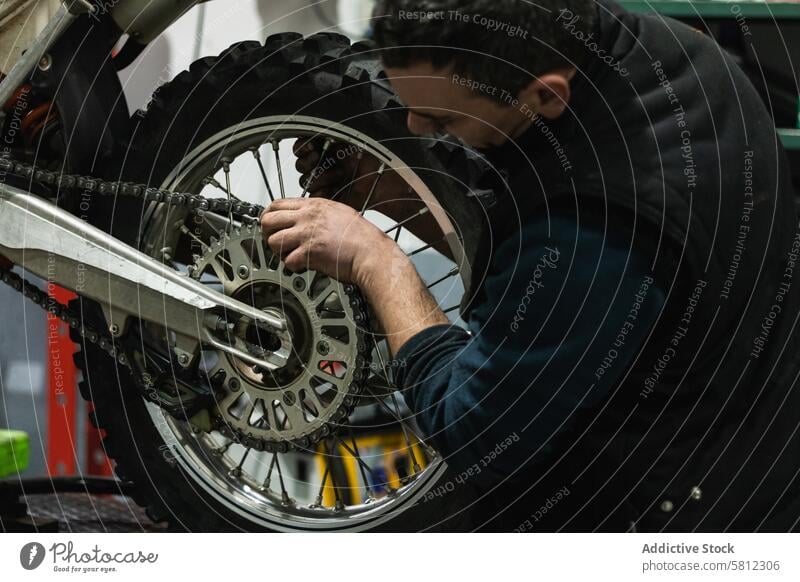 Motorradmechaniker wechselt in der Werkstatt die Motorradkette Mann Wandel & Veränderung anketten Mechaniker Garage Arbeit Flugzeugwartung Reparatur Beruf Job