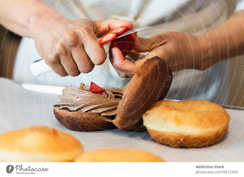 Crop-Bäckerin bereitet köstliche vegane Biskuitkuchen am Tisch zu Schwamm Kuchen Bäckerei Koch vorbereiten Veganer Dessert Erdbeeren geschnitten gepeitscht