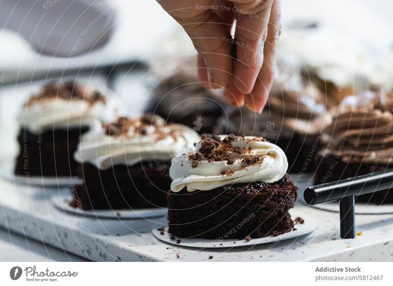 Crop-Bäcker bei der Zubereitung eines veganen Desserts in der Küche bestäuben Schokolade Kuchen Schwamm dekorieren eingießen Veganer Bäckerei appetitlich Koch