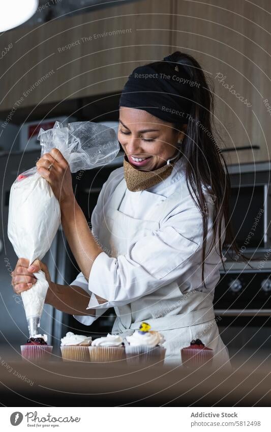 Köchin beim Verzieren von Törtchen mit Schlagsahne Frau Cupcake Bäcker gepeitscht Sahne drücken Backwarenbeutel Bäckerei Veganer Dessert Koch süß Leckerbissen