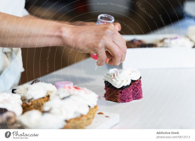 Crop-Bäckerin dekoriert Samttorte mit Sahne Kuchen bestäuben dekorieren Dessert Veganer Bäckerei drücken Gebäck Koch Küchenchef lecker geschmackvoll Gastronomie