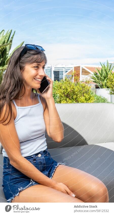 Eine Frau sitzt auf einer Couch und telefoniert mit ihrem Handy. Vertikale Aufnahme. Leerzeichen kopieren Erwachsener attraktiv Hintergrund Schönheit schwarz