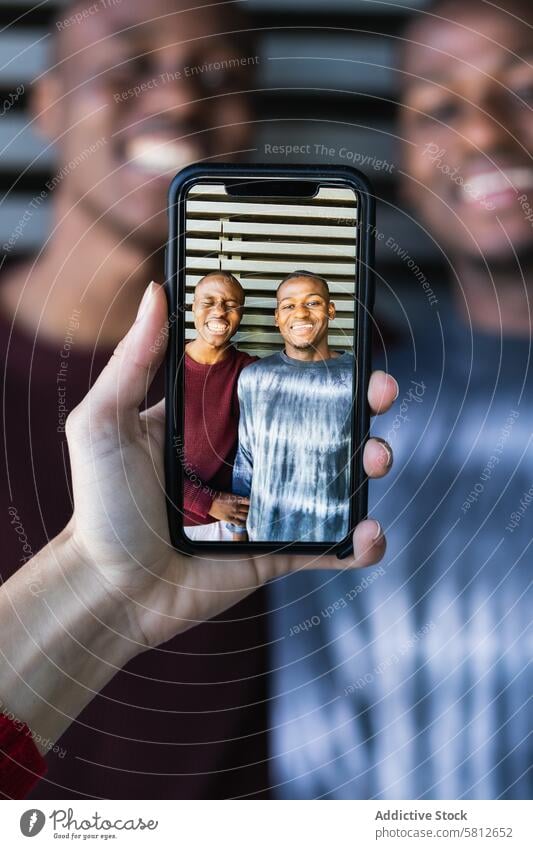 Person, die mit dem Smartphone ein Foto von schwarzen Freunden macht Männer bester Freund benutzend positiv fotografieren heiter Zusammensein sorgenfrei