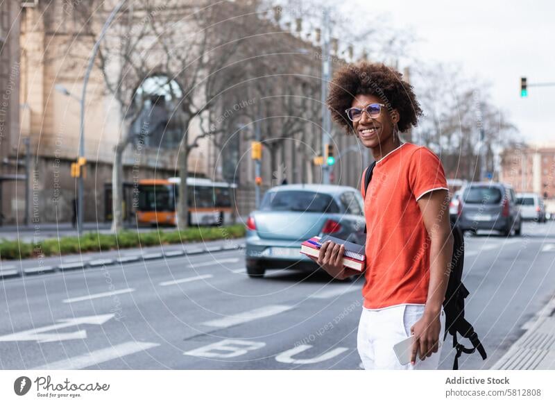 Lächelnder junger schwarzer männlicher Student an einer Bushaltestelle in der Stadt Mann warten Schüler Stil Straße urban cool Bildung ernst Inhalt