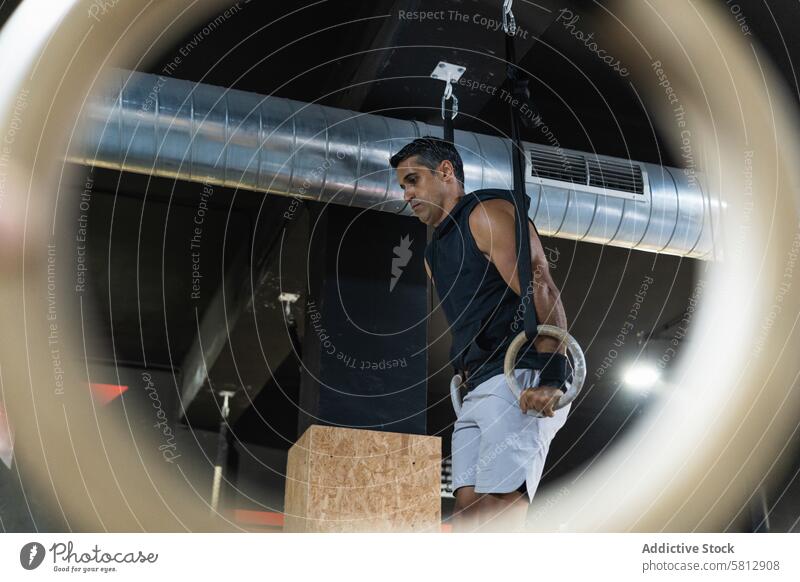 Spanischer Sportler beim Training mit Gymnastikringen Athlet gymnastisch Ring Fitnessstudio Übung Gerät üben sportlich Mann Sportkleidung Sportbekleidung