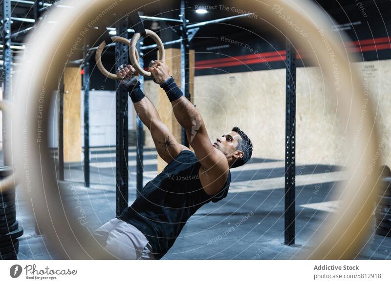 Spanischer Sportler beim Training mit Gymnastikringen Athlet gymnastisch Ring Fitnessstudio Übung Gerät üben sportlich Mann Sportkleidung Sportbekleidung