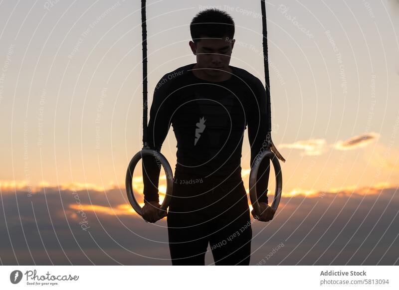 Sportler beim Training an den Gymnastikringen Turner Übung Ring Athlet Sonnenuntergang Bestimmen Sie jung Mann asiatisch ethnisch gymnastisch physisch Ausdauer