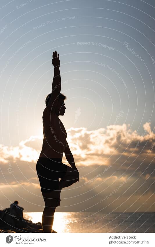 Mann übt Yoga-Asana bei Sonnenuntergang Baumhaltung vriksasana Silhouette üben Pose Gleichgewicht Harmonie Zen stehen männlich Lifestyle Wellness Wohlbefinden