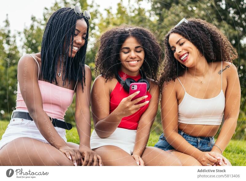 Afroamerikanische Freunde genießen den Sommer gemeinsam und nutzen das Smartphone Afroamerikaner Vielfalt Jugend Anschluss Mitteilung Freude lachen Fröhlichkeit