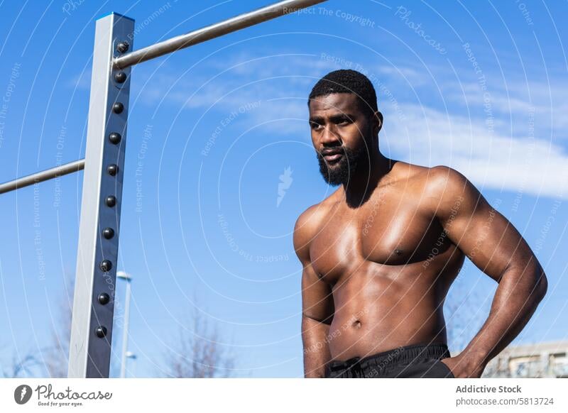 Starker ethnischer Sportler ruht sich beim Training auf dem Sportplatz aus nackter Torso stark ruhen muskulös Wellness Hand an der Hüfte Mann ohne Hemd