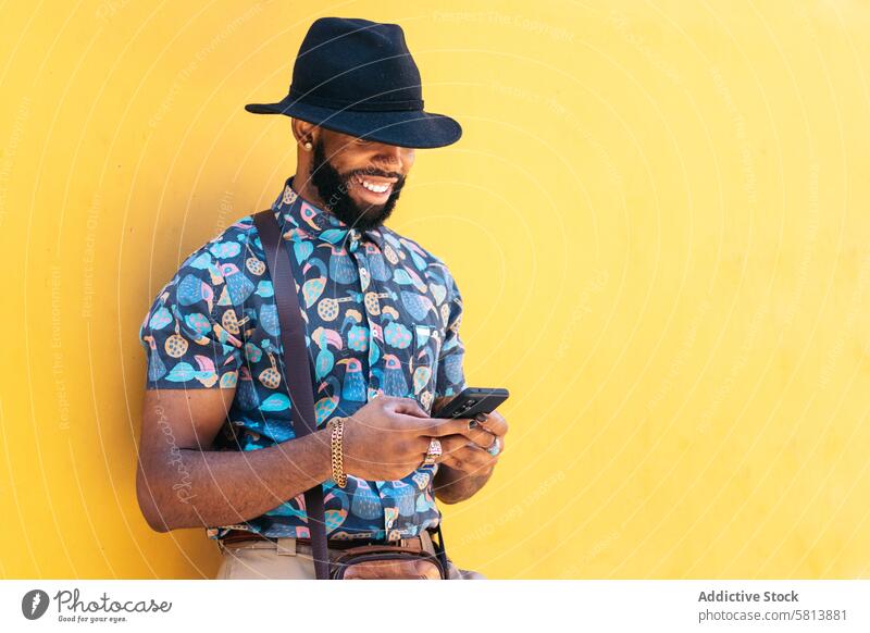 Stilvoller schwarzer Mann mit Smartphone im Freien auf gelbem Hintergrund Technik & Technologie Lifestyle Großstadt jung Straße urban Telefon Mobile männlich