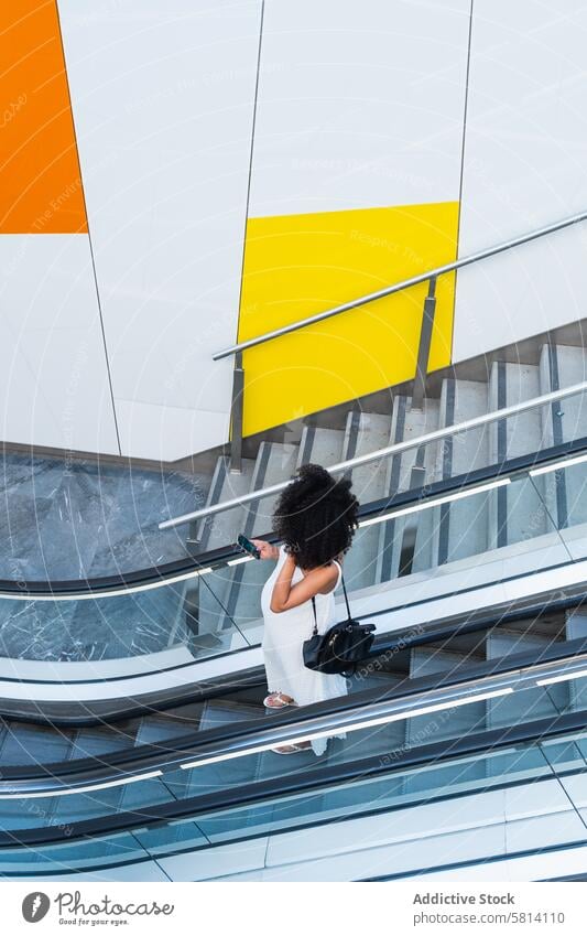 Schwangere schwarze Frau durchsucht Smartphone auf Rolltreppe schwanger benutzend Bauch Browsen Anschluss vorwegnehmen online warten Schwangerschaft erwarten