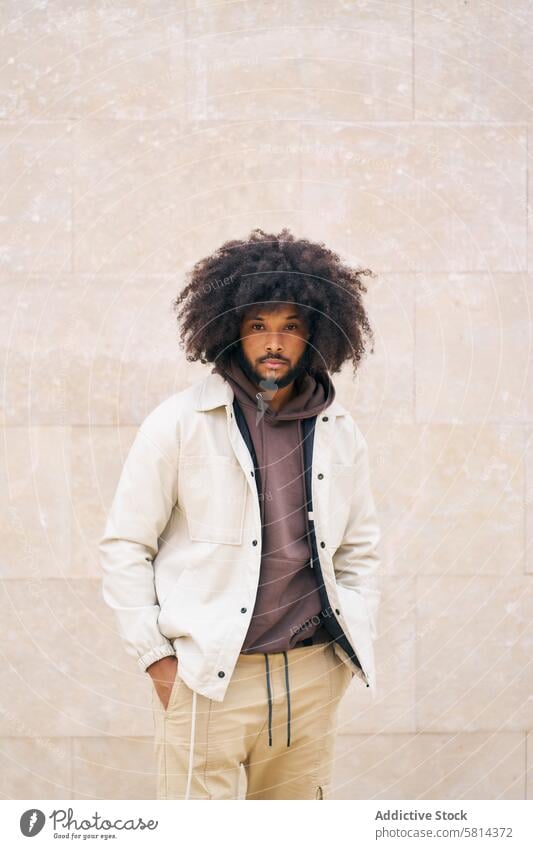 Porträt eines jungen Mannes mit Afro-Haar und Händen in den Taschen, der in die Kamera schaut Afro-Look Blick Fotokamera Erwachsener Person männlich Männer Mode