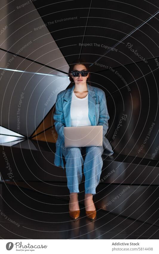 Frau mit Sonnenbrille beim Surfen auf dem Laptop im Studio futuristisch 3d Browsen Atelier modern Design online Internet Apparatur benutzend Gerät elegant Wand