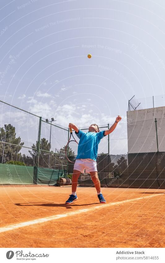 Kleiner Junge spielt Tennis auf einem unbefestigten Platz und macht einen Aufschlag Aktivität Sport Spiel Remmidemmi Kind Person Spieler spielen Athlet Training