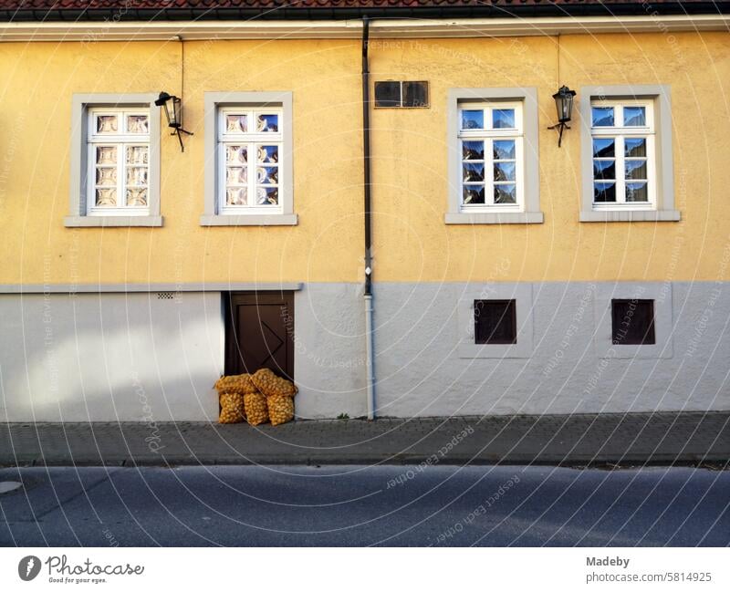 Kartoffelsack vor der alten Kellertür eines denkmalgeschützten Altbau mit Fassade in Beige und Naturfarben mit Sprossenfenster in Oerlinghausen am Hermannsweg im Teutoburger Wald in Ostwestfalen-Lippe