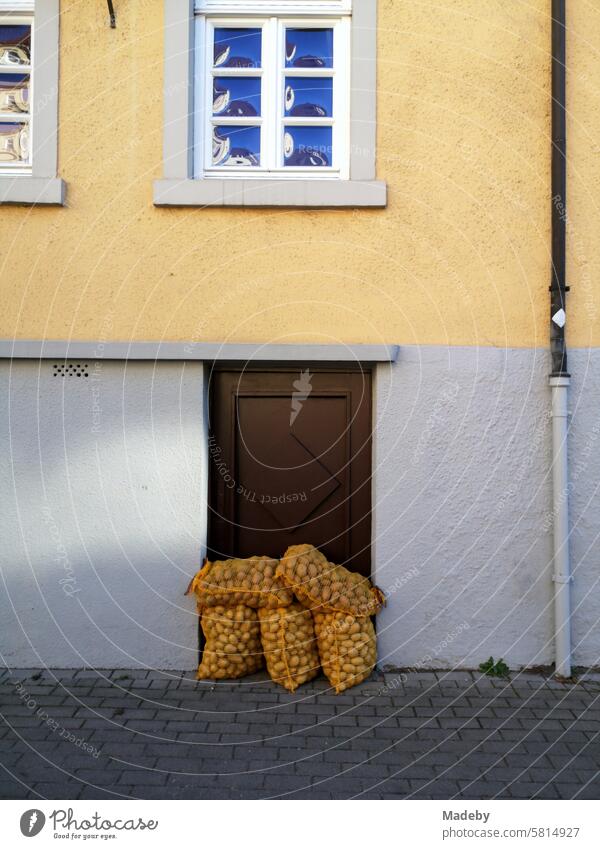 Kartoffelsack vor der alten Kellertür eines denkmalgeschützten Altbau mit Fassade in Beige und Naturfarben mit Sprossenfenster in Oerlinghausen am Hermannsweg im Teutoburger Wald in Ostwestfalen-Lippe