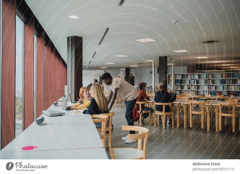 Verschiedene Gruppenmitglieder unterhalten sich und benutzen ein Netbook in der Bibliothek Schüler Anweisung Zusammensein Gruppenkamerad Laptop lernen Talkrunde