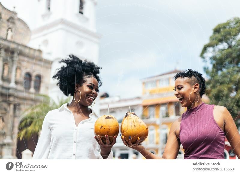 Lateinamerikanische Frauen, die sich in der Stadt amüsieren und Kokosnüsse trinken Glück jung Sommer im Freien Menschen Freizeit Lifestyle freudig Freude