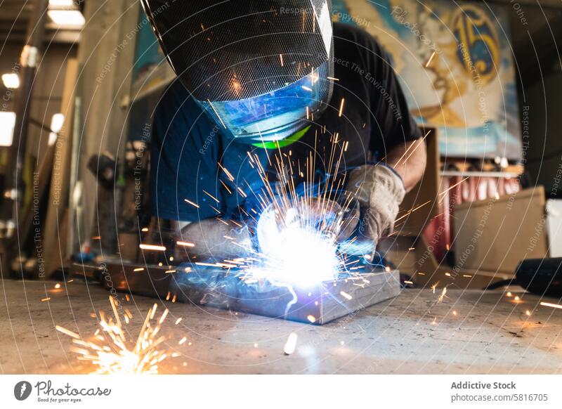 Schweißer mit Schutzhelm beim Schweißen von Metallteilen in der Werkstatt Schweißnaht Funken Mann Metallbearbeitung behüten Maschine Hobelbank männlich