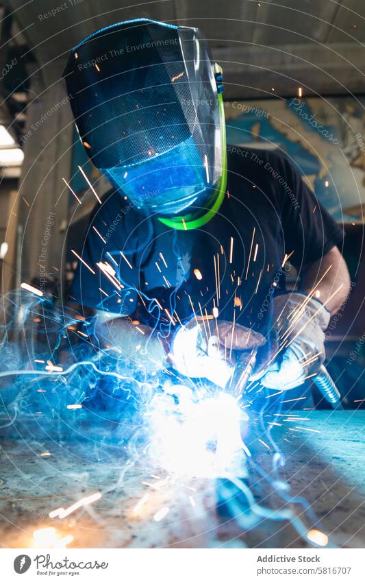 Schweißer mit Schutzhelm beim Schweißen von Metallteilen in der Werkstatt Schweißnaht Funken Mann Metallbearbeitung behüten Maschine Hobelbank männlich