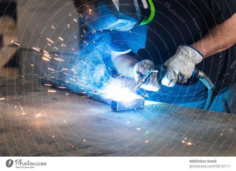 Schweißer mit Schutzhelm beim Schweißen von Metallteilen in der Werkstatt Schweißnaht Funken Mann Metallbearbeitung behüten Maschine Hobelbank männlich