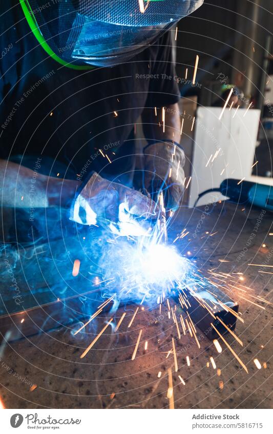 Schweißer mit Schutzhelm beim Schweißen von Metallteilen in der Werkstatt Schweißnaht Funken Mann Metallbearbeitung behüten Maschine Hobelbank männlich