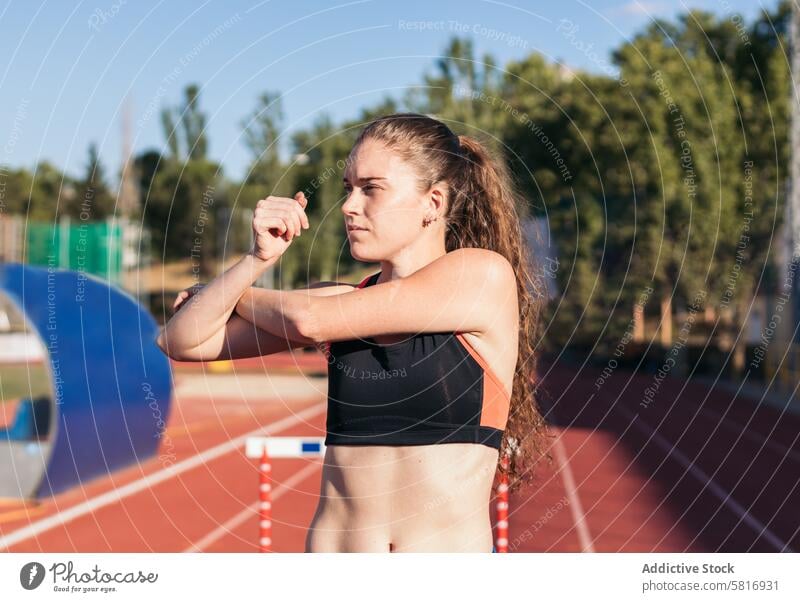 Weibliche Athletin beim Dehnen auf einer Leichtathletikbahn. Fitness Lifestyle Sport Bahn Läufer Training Übung Gesundheit Frau aktiv passen Person im Freien