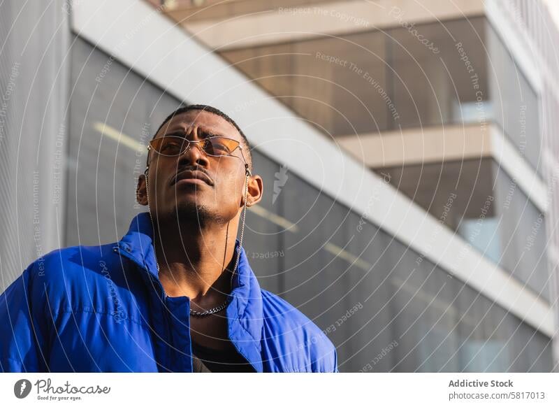 Stilvoller schwarzer Mann mit Sonnenbrille auf der Straße orange trendy Outfit Bestimmen Sie cool urban männlich ethnisch Metallwand Afroamerikaner