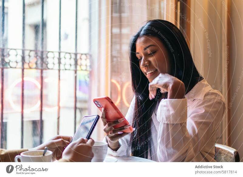 Lateinamerikanische Frau sitzt in einem Café und benutzt ihr Smartphone. Termin & Datum Kantine Restaurant Lifestyle Sitzung Datierung Bar sprechend Großstadt