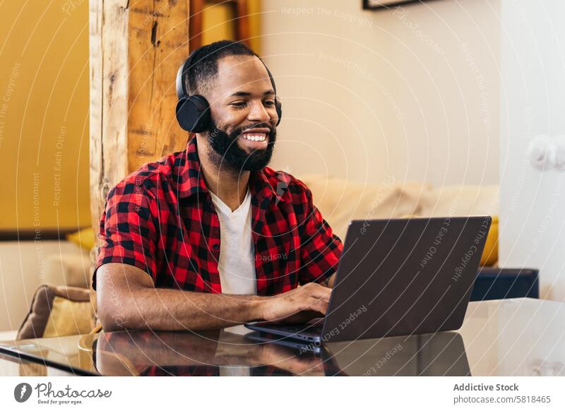 Afroamerikanischer Mann, der von zu Hause aus mit seinem Laptop arbeitet Telearbeit Computer Afroamerikaner heimwärts Internet freiberuflich abgelegen online