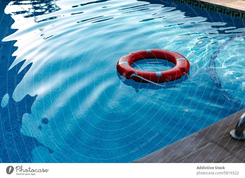 Roter Rettungsring schwimmt in einem ruhigen blauen Pool Sicherheit Wasser Ring Lebensrettung rot schwimmen Flotationsvorrichtung retten Schwimmer Windstille