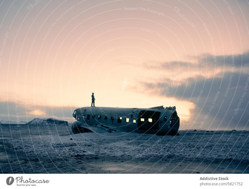 Person auf verlassenem Flugzeugwrack in Island in der Abenddämmerung Wrackteile desolat Figur Silhouette Landschaft Himmel Pastell Verlassen einsiedlerisch