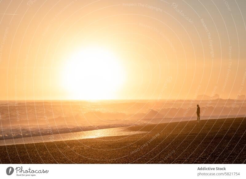 Silhouette einer Person an einem Strand bei Sonnenuntergang in Island goldene Stunde Meer Wellen Ufer Küstenlinie im Freien Landschaft malerisch Natur Schönheit