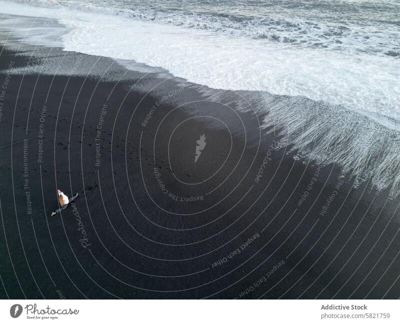 Einsame Frau am schwarzen Sandstrand in Island schwarzer Sand Strand winken Natur Einsamkeit schlicht Küstenstreifen Meereslandschaft Brandung Textur Ufer