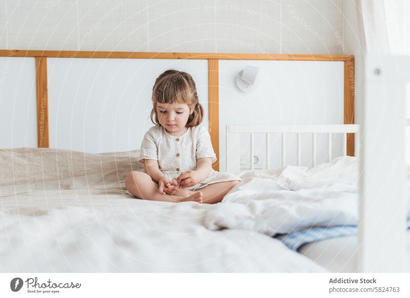 Unauffälliger Moment eines Kleinkindes auf dem Bett Schlafzimmer Kind spielen Fuß allein nachdenklich sonnenbeschienen sehr wenige Möbel Morgen Streu gemütlich