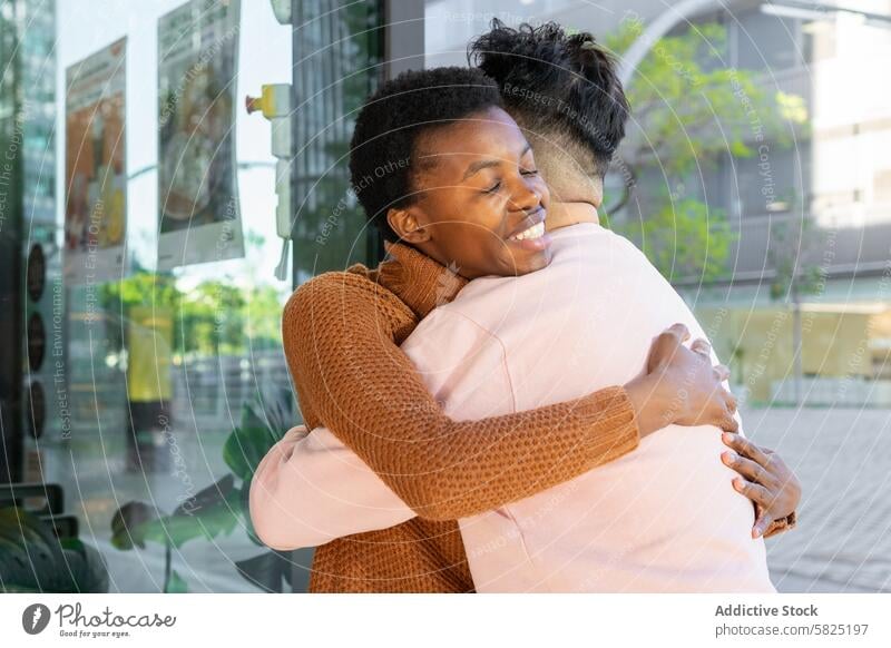 Freudiges Wiedersehen zweier Freunde in städtischer Umgebung Freundschaft Umarmen Umarmung Großstadt urban Glück Zuneigung Freude Frau Afrikanisch sonnig Mann