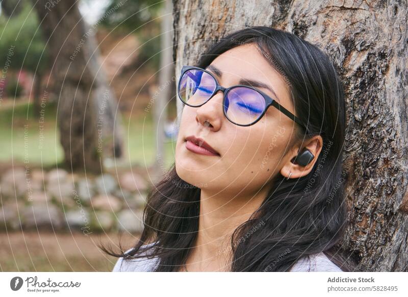 Gelassener Moment - junge Frau genießt die Ruhe der Natur Gelassenheit Erholung Park friedlich Baum Augen geschlossen Freizeit im Freien Brille