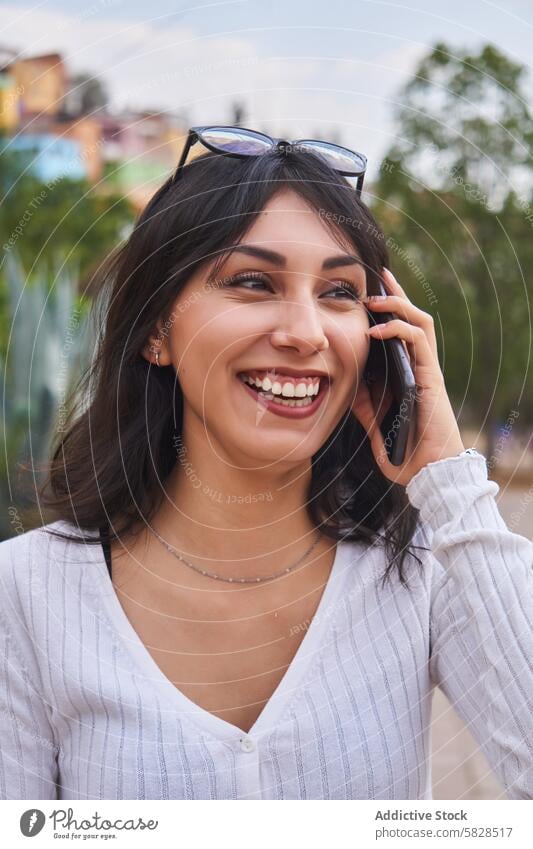 Lächelnde Frau genießt Telefongespräch im Freien Gespräch Mobile Park lachen Konnektivität Fröhlichkeit Mitteilung Technik & Technologie Funktelefon Smartphone