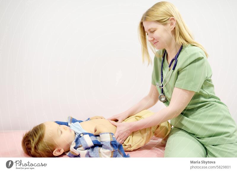 Cute Kleinkind Junge ist bei einem Termin mit Kinderarzt. Arzt Gastroenterologe palpating Bauch des kleinen Kindes Patienten auf der Couch im medizinischen Büro liegen. Gastroenterologische Erkrankungen bei Kindern