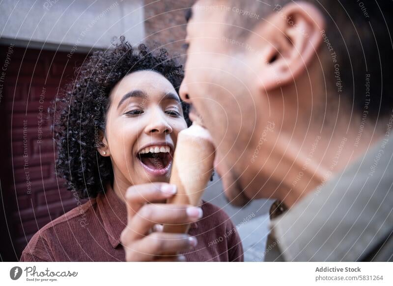 Ein multiethnisches Paar teilt sich ein Eis auf einer Straße in Madrid, Spanien interrassisch Chinesisch hispanisch Speiseeis Teilen freudig Glück Lächeln