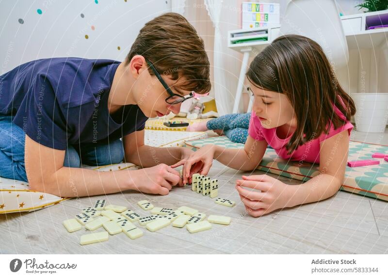 Geschwister spielen zu Hause eine Partie Domino Kind Geschwisterkind Spiel Dominosteine Schlafzimmer Stock Spaß Bonden Familie Bruder Schwester im Innenbereich