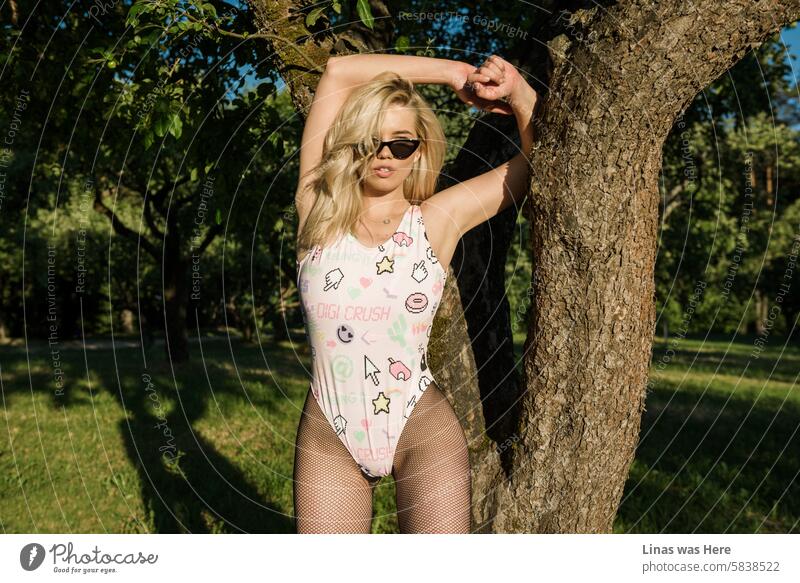 Ein wunderschönes blondes Fotomodell in einem rosa Badeanzug posiert makellos vor der Kamera. Sie trägt eine Sonnenbrille und sieht genauso aus wie die legendäre Claudia Schiffer. Oder doch nicht?