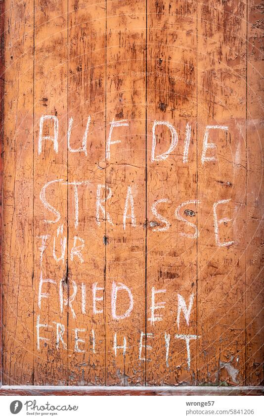 Für Frieden und Freiheit Aufruf Aufforderung Kreideschrift Bretterwand Holzwand Holztür Wand Menschenleer Fassade Außenaufnahme Farbfoto Nahaufnahme braun