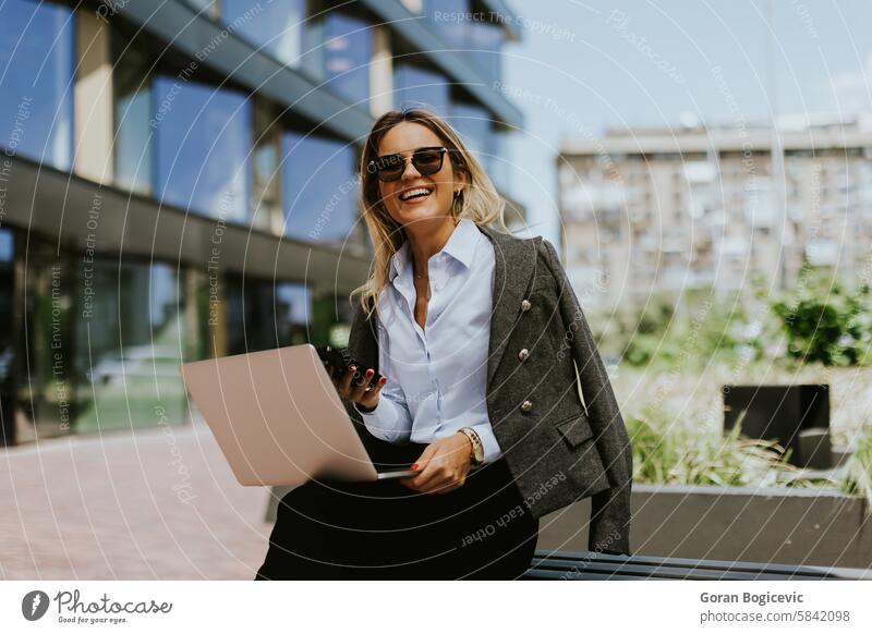 Professionelle Geschäftsfrau arbeitet am Laptop vor einem modernen Bürogebäude im Tageslicht Architektur Bank Blazer Gebäude Business Karriere Großstadt